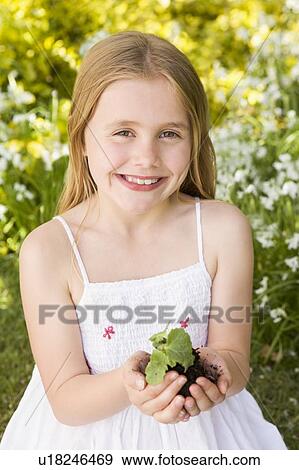 Young girl outdoors holding plant smiling View Large Photo Image Stock Photo - Young girl outdoors holding plant smiling. Fotosearch