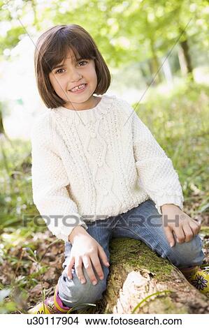 Young girl outdoors in woods sitting on log smiling View Large Photo Image Picture - Young girl outdoors in woods sitting on log smiling. Fotosearch