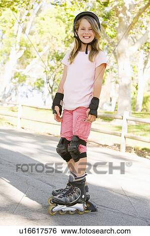 Stock Photograph - Young girl outdoors on inline skates smiling. Fotosearch