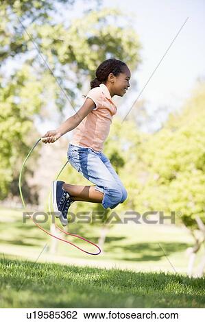 Young girl using skipping rope outdoors smiling View Large Photo Image Stock Image - Young girl using skipping rope outdoors smiling. Fotosearch