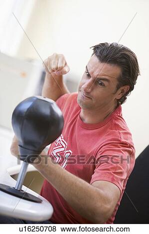Businessman in office using small punching bag to relieve stress View Large Photo Image Stock Photo - Businessman in office using small punching bag to relieve stress. Fotosearch