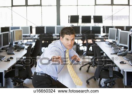 Picture - Businessman standing in karate stance in computer room. Fotosearch