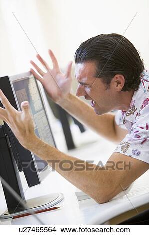 Picture - Man in computer room frustrated at monitor. Fotosearch