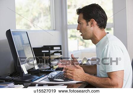 Man in home office using computer looking frustrated View Large Photo Image Stock Photo - Man in home office using computer looking frustrated. Fotosearch