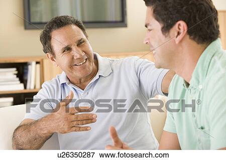 Stock Photo - Two men in living room talking and smiling. Fotosearch