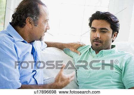 Stock Photo - Two men in living room talking (high key). Fotosearch