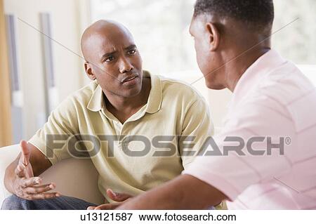 Stock Photo - Two men in living room talking. Fotosearch