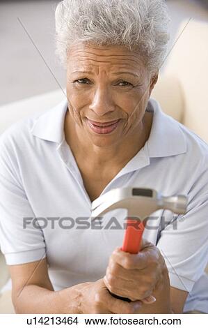 Picture - Woman holding hammer looking unsure. Fotosearch