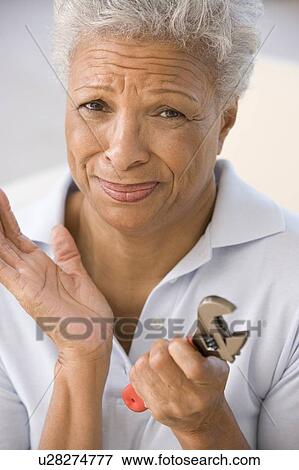 Woman holding wrench looking unsure View Large Photo Image Stock Photo - Woman holding wrench looking unsure. Fotosearch