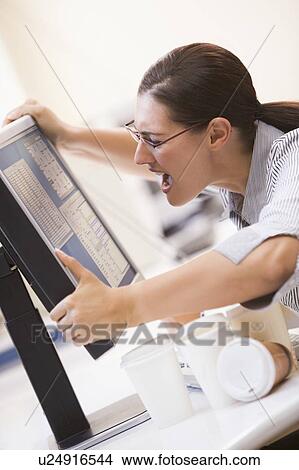 Picture - Woman in computer room grabbing her monitor and screaming. Fotosearch