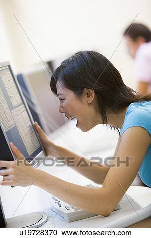 Woman in computer room holding monitor and smiling View Large Photo Image Stock Image - Woman in computer room holding monitor and smiling. Fotosearch