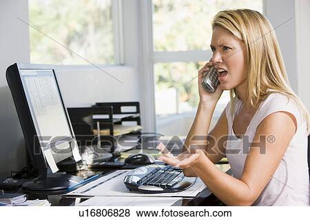 Woman in home office with computer using telephone frowning View Large Photo Image Stock Photo - Woman in home office with computer using telephone frowning. Fotosearch