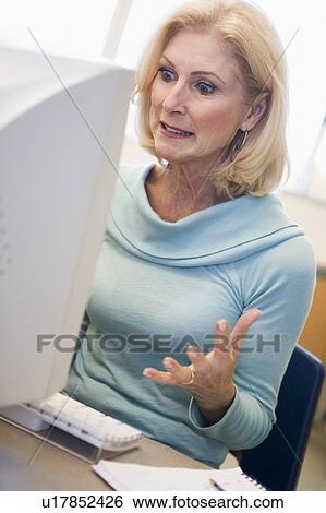 Woman sitting at computer frustrated (high key) View Large Photo Image Stock Photograph - Woman sitting at computer frustrated (high key). Fotosearch
