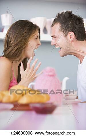 Stock Photo - Young couple sitting at a table arguing. Fotosearch