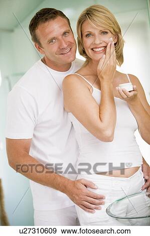 Stock Photo - Couple in bathroom with face cream smiling. Fotosearch