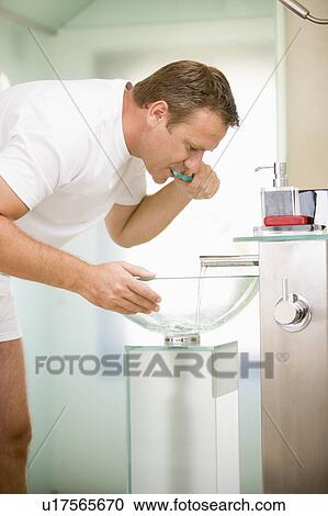 Stock Image - Man in bathroom brushing teeth. Fotosearch