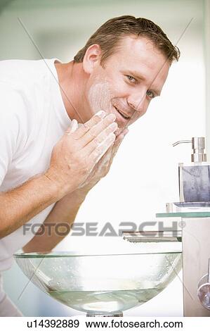 Stock Photo - Man in bathroom washing face. Fotosearch