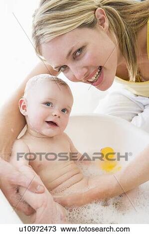 Stock Image - Mother giving baby bubble bath smiling. Fotosearch