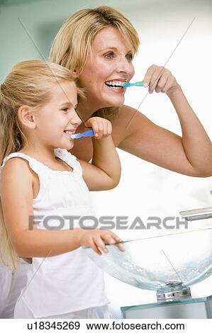 Woman and young girl in bathroom brushing teeth View Large Photo Image Stock Photo - Woman and young girl in bathroom brushing teeth. Fotosearch