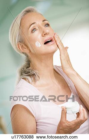 Stock Photo - Woman applying face cream. Fotosearch