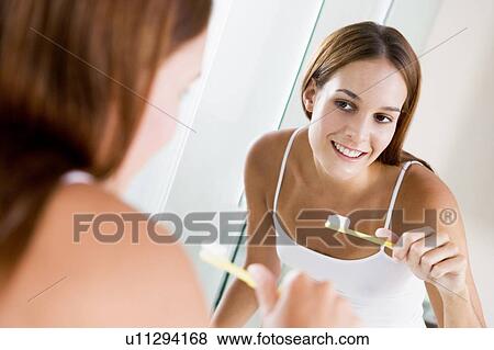 Woman in bathroom brushing teeth and smiling View Large Photo Image Stock Photo - Woman in bathroom brushing teeth and smiling. Fotosearch