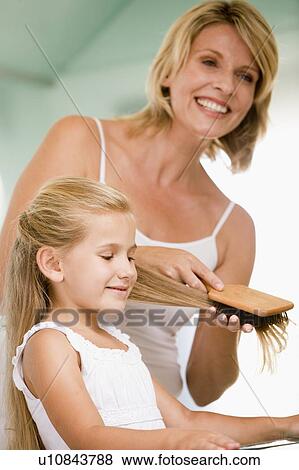 Stock Photo - Woman in bathroom brushing young girl's hair. Fotosearch
