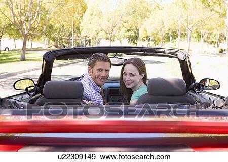 Stock Photo - Couple in convertible car smiling. Fotosearch