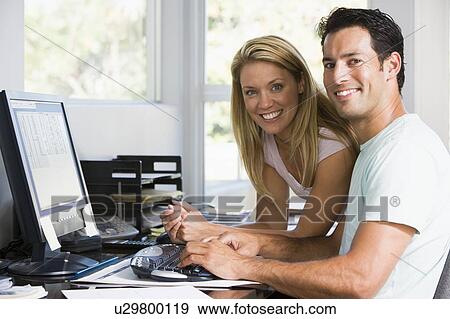 Stock Photo - Couple in home office with computer smiling. Fotosearch