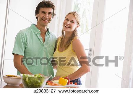 Couple in kitchen cutting up vegetables and smiling View Large Photo Image Stock Photo - Couple in kitchen cutting up vegetables and smiling. Fotosearch