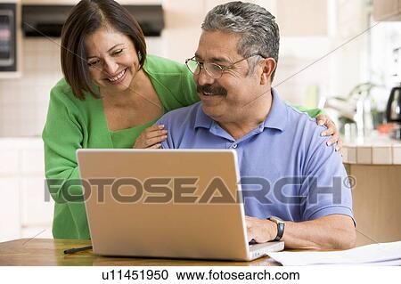 Couple in kitchen with laptop smiling View Large Photo Image Stock Image - Couple in kitchen with laptop smiling. Fotosearch