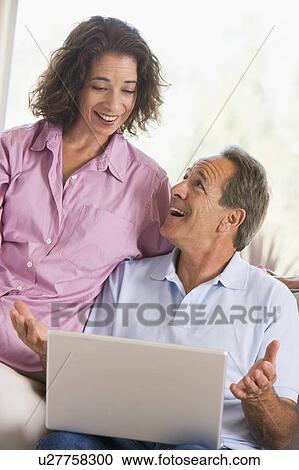 Couple in living room with laptop smiling View Large Photo Image Stock Image - Couple in living room with laptop smiling. Fotosearch