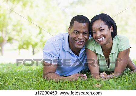 Stock Photo - Couple lying outdoors smiling. Fotosearch