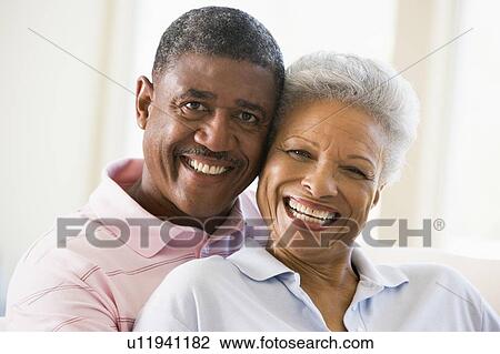 Couple relaxing in living room and smiling View Large Photo Image Stock Image - Couple relaxing in living room and smiling. Fotosearch