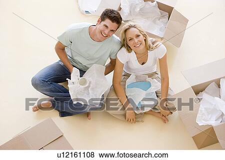 Couple sitting on floor by open boxes in new home smiling View Large Photo Image Stock Photo - Couple sitting on floor by open boxes in new home smiling. Fotosearch