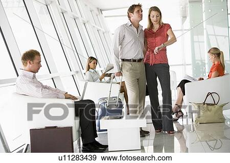 Stock Photo - Couple waiting with other airline passengers in departure gate. Fotosearch