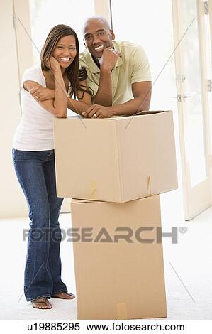 Stock Photography - Couple with boxes in new home smiling. Fotosearch