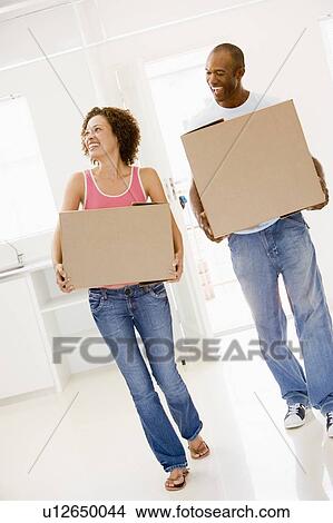 Couple with boxes moving into new home smiling View Large Photo Image Picture - Couple with boxes moving into new home smiling. Fotosearch