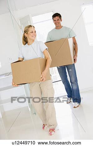 Stock Image - Couple with boxes moving into new home smiling. Fotosearch