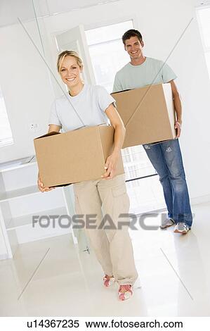 Couple with boxes moving into new home smiling View Large Photo Image Stock Photography - Couple with boxes moving into new home smiling. Fotosearch