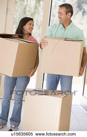 Couple with boxes moving into new home smiling View Large Photo Image Stock Photography - Couple with boxes moving into new home smiling. Fotosearch