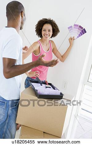 Stock Photography - Couple with paint swatches in new home smiling. Fotosearch