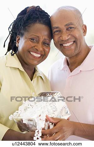 Husband and wife holding gift smiling View Large Photo Image Picture - Husband and wife holding gift smiling. Fotosearch