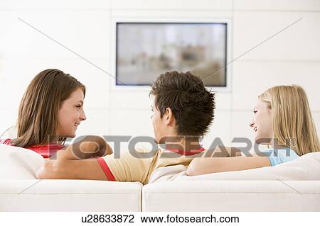 Three friends in living room watching television smiling View Large Photo Image Stock Image - Three friends in living room watching television smiling. Fotosearch