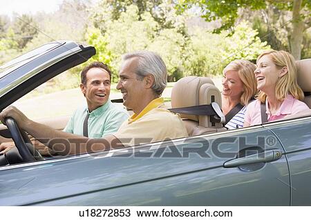 Stock Image - Two couples in convertible car smiling. Fotosearch