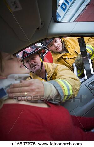 Fireman helping woman with neck brace while another fireman uses the jaws of life on a car door (selective focus) View Large Photo Image Stock Photography - Fireman helping woman with neck brace while another fireman uses the jaws of life on a car door (selective focus). Fotosearch