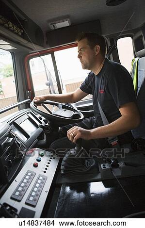 Picture - Fireman in fire engine holding steering wheel. Fotosearch