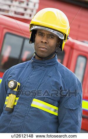 Fireman standing by fire engine wearing helmet View Large Photo Image Stock Photo - Fireman standing by fire engine wearing helmet. Fotosearch