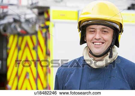 Fireman standing by fire engine wearing helmet View Large Photo Image Stock Photograph - Fireman standing by fire engine wearing helmet. Fotosearch