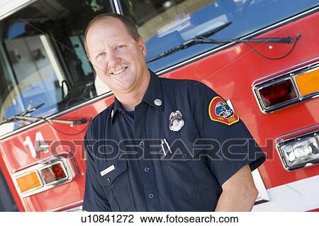 Stock Image - Fireman standing in front of fire engine. Fotosearch