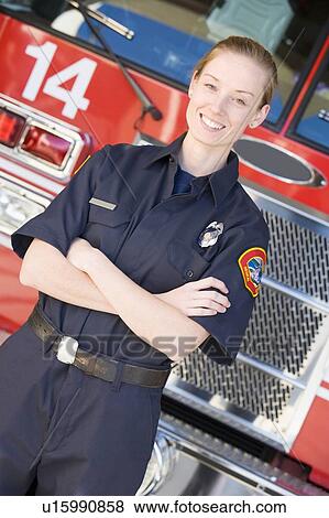 Stock Photo - Firewoman standing in front of fire engine. Fotosearch